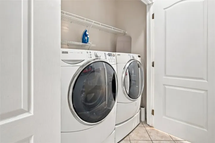 Tiled flooring and integrated shelving maximize utility in this dedicated laundry space.