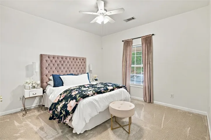 Soft carpeting pairs with a multi-pane window to create a serene, light-filled bedroom atmosphere.