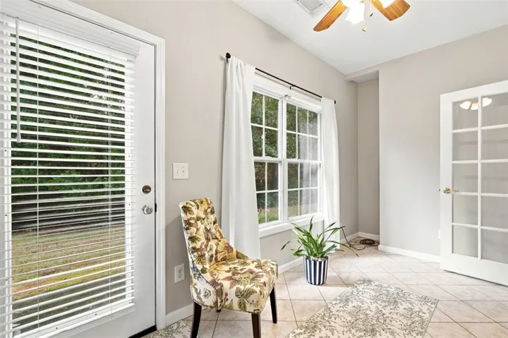 Gleaming tile floors and multi-lite French doors elevate this versatile sun-drenched space.
