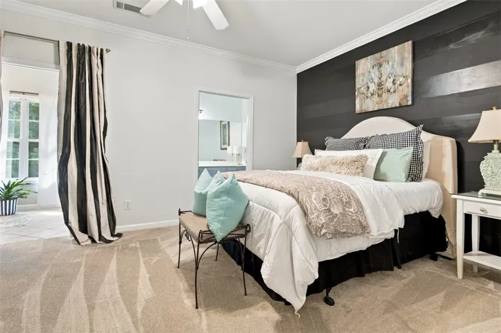 Plush carpeting anchors this spacious bedroom featuring clean lines and crown molding details.