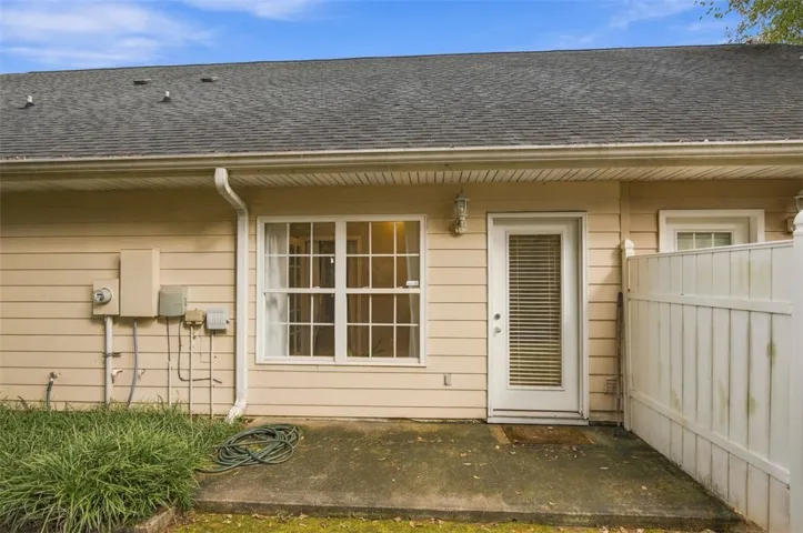 A private concrete patio sits behind the home, bordered by vinyl privacy fencing.