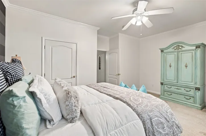 Crown molding and soft carpeting elevate the serene atmosphere of this inviting bedroom.