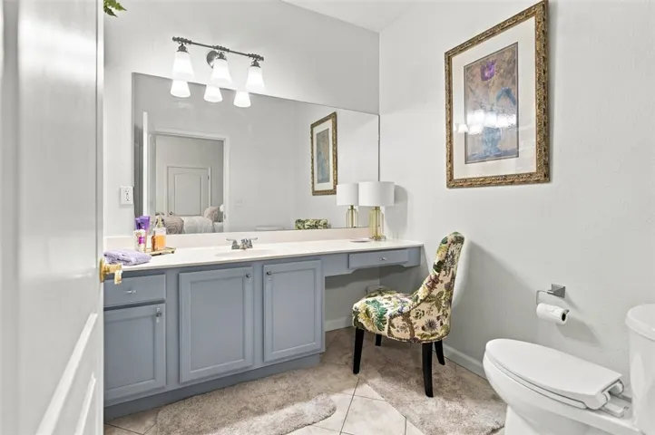 A spacious vanity area with built-in cabinetry and stone counters anchors this bright bathroom.
