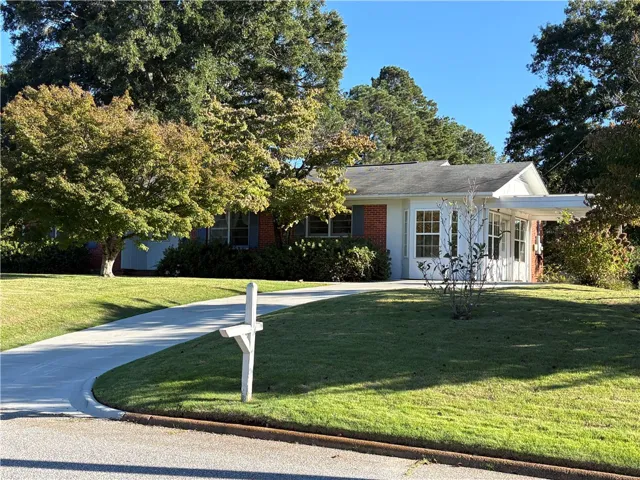 Mature trees frame this classic single-story brick home