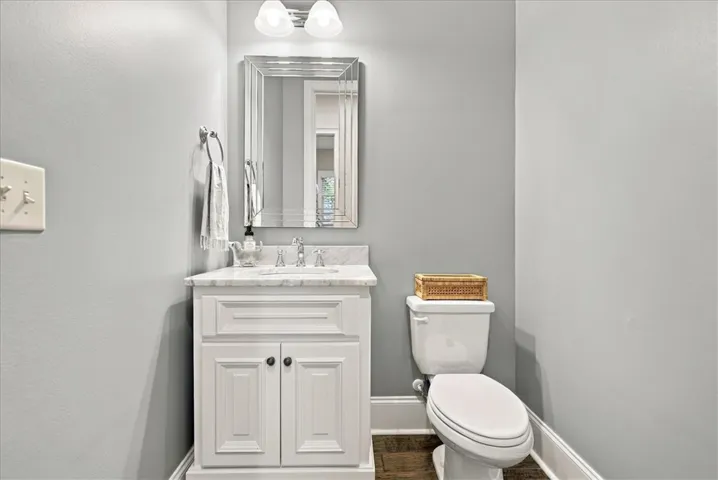 Smooth crown-molding baseboards frame the handsome wood flooring of this convenient powder room.