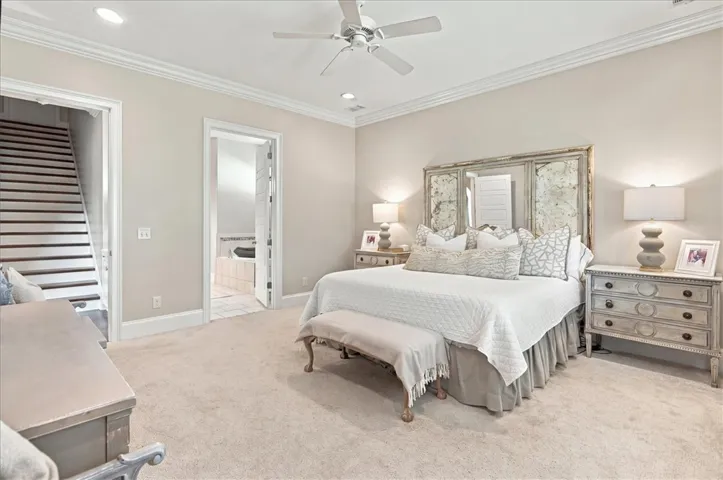 Crown molding and plush carpeting define this spacious primary suite with an attached bath.