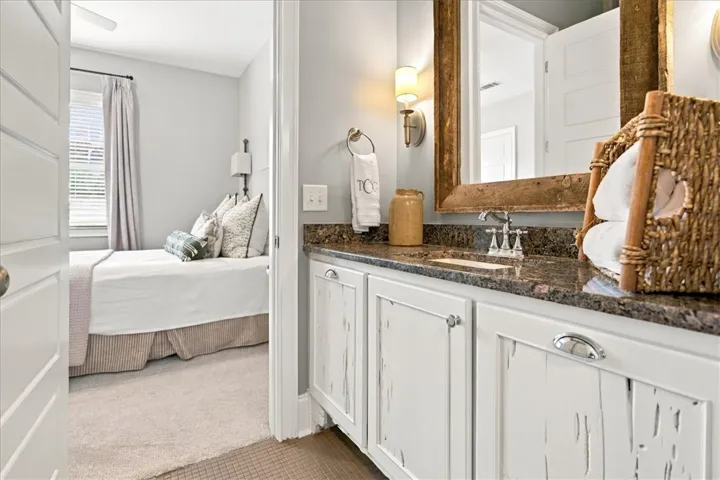 A polished granite vanity and distressed cabinetry ground this elegant bathroom design.