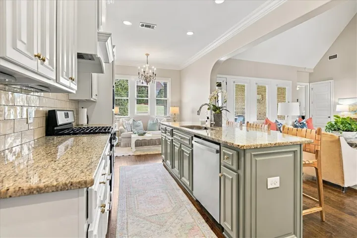 Gleaming stone countertops and a spacious central island anchor this beautifully appointed kitchen design.