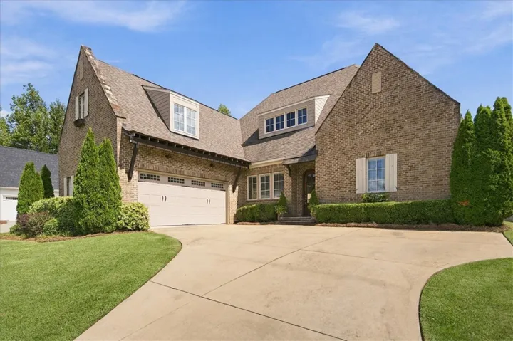 A sweeping concrete driveway leads to this stately brick home with a multi-gabled roofline.