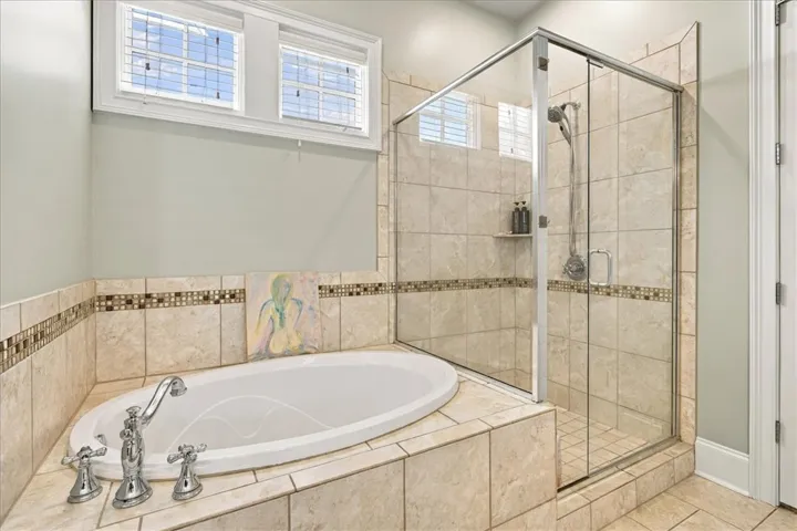Tiled surrounds frame a built-in soaking tub and a glass-enclosed walk-in shower.