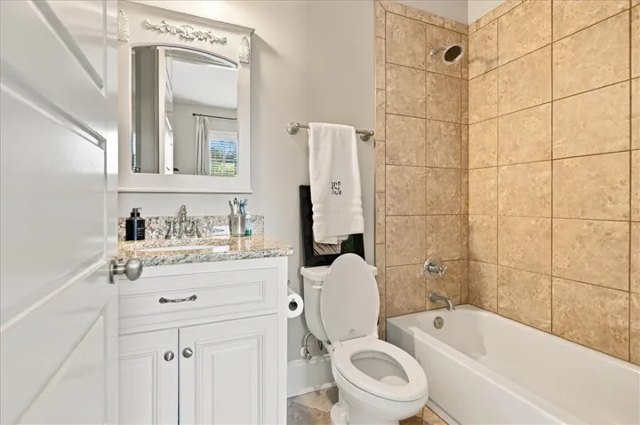 A well-appointed bathroom features stone countertops and a tiled tub surround.