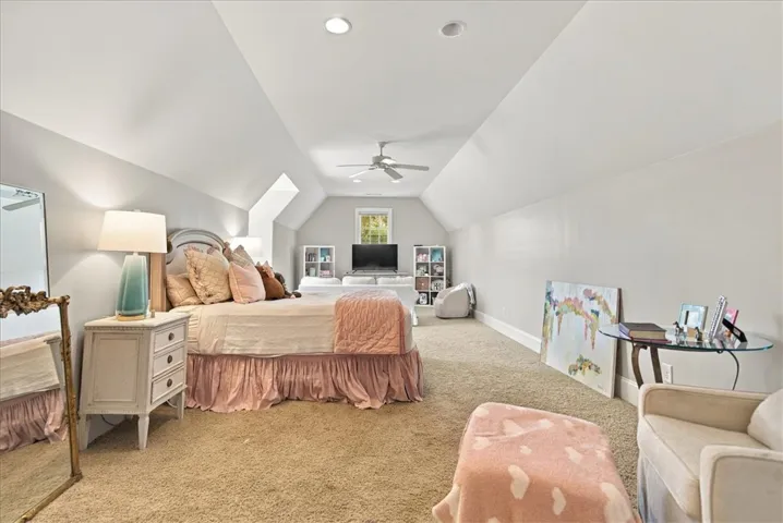 Sloped ceilings frame this top-level suite featuring plush carpeting and recessed lighting.