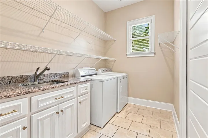 Ample wire shelving and a handy utility sink maximize storage in this tiled laundry room.