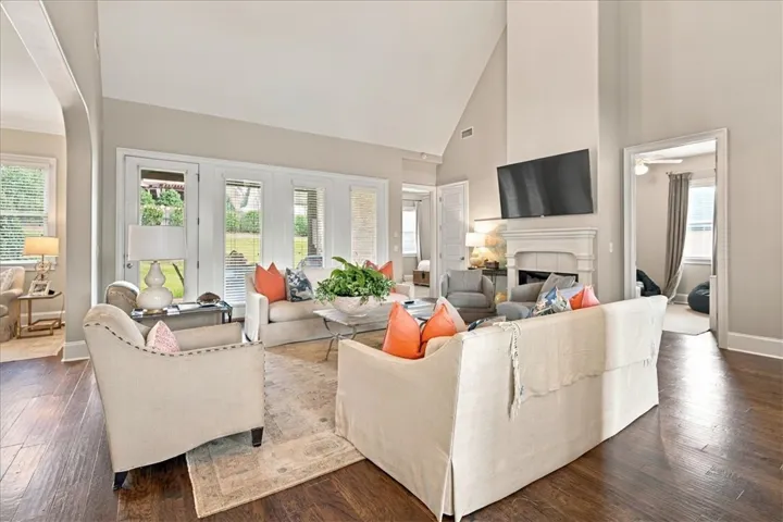 Rich hardwood floors anchor this airy living room with a vaulted ceiling and fireplace.