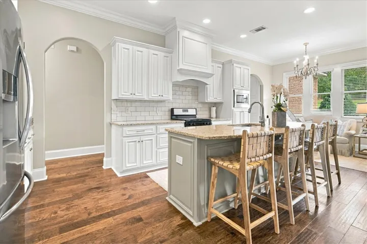 Rich wood floors complement custom white cabinetry and a central island with granite counters.