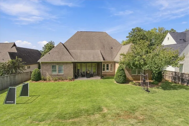 An expansive green lawn stretches behind this classic brick home under a clear blue sky.