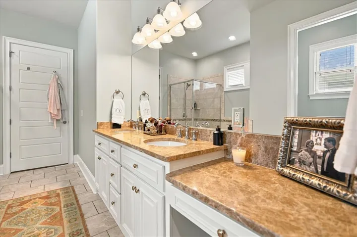 Polished stone countertops complement a double vanity and tiled flooring in this modern bathroom.
