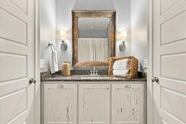 Distressed cabinetry and natural stone counters anchor this charming powder room vanity nook.