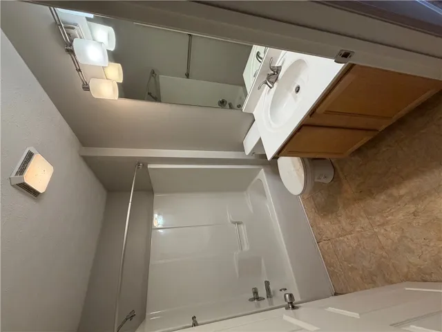 Functional layout incorporates a combined tub and shower alongside a wood vanity.