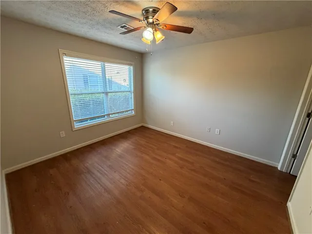 Rich wood flooring runs throughout this versatile bedroom anchored by a large, central window.