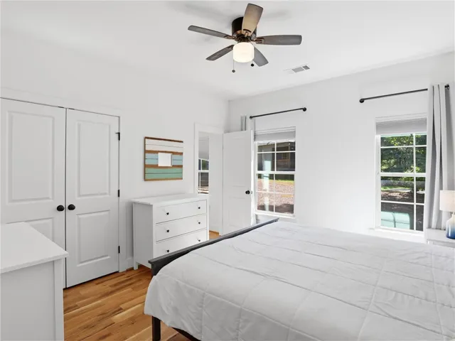 Rich hardwood flooring complements the crisp white walls and dual windows in this peaceful bedroom.