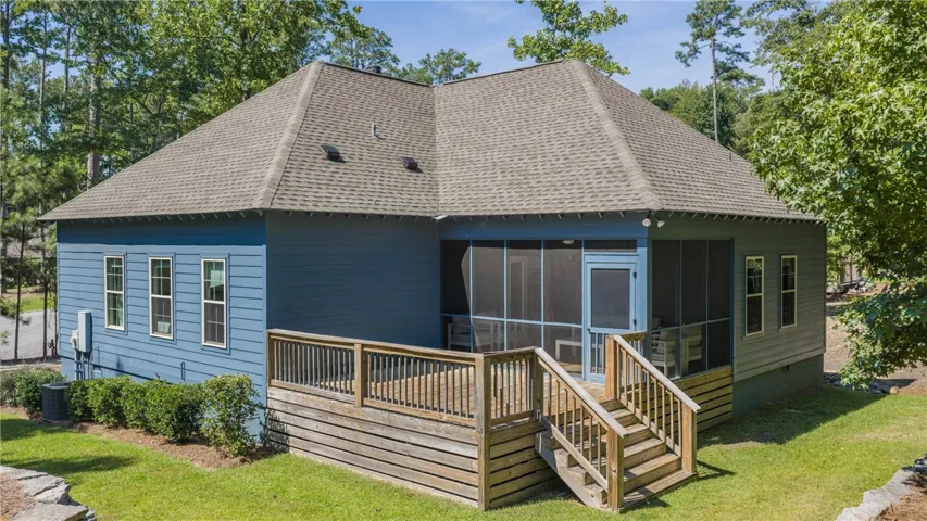 A spacious wooden deck and screened porch extend from the rear of this modern home.