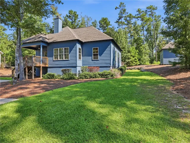 Lush green lawns and mature trees frame this classic siding home with elevated wooden decking.