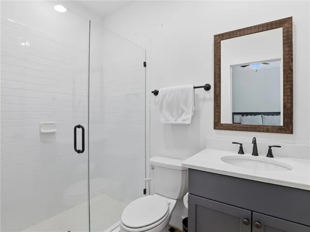 A glass-enclosed walk-in shower sits adjacent to a modern vanity with dark cabinetry.