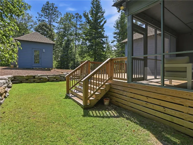 An inviting wooden deck with stairs connects the screened porch to a grassy backyard.