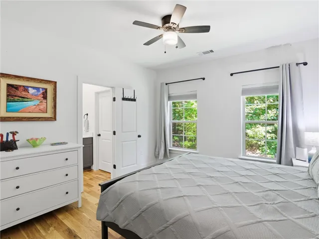 Natural light streams through twin windows onto beautiful hardwood floors in this comfortable bedroom.