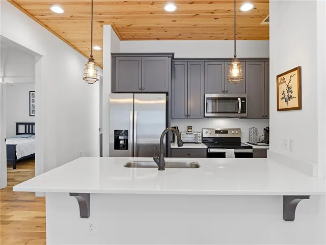 Warm wood ceilings balance the sleek stone counters and modern cabinetry in this culinary space.