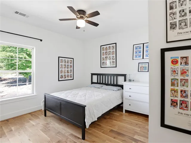 Warm hardwood flooring and a large window create a welcoming atmosphere in this bedroom.