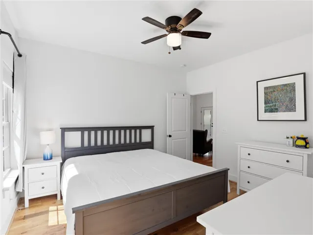 Rich hardwood flooring anchors this inviting bedroom illuminated by natural light.