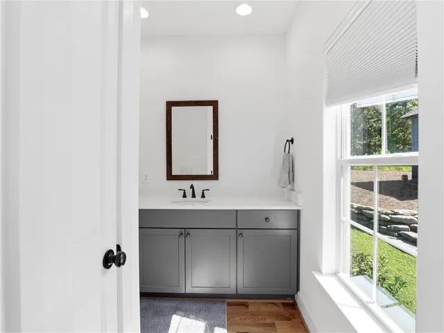 Natural light streams across rich wood flooring in this contemporary bathroom setup.
