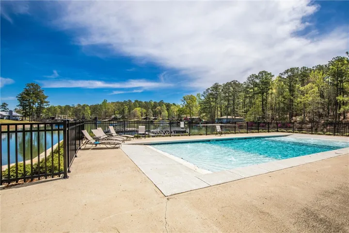 A sparkling swimming pool overlooks the tranquil lake surrounded by mature trees.