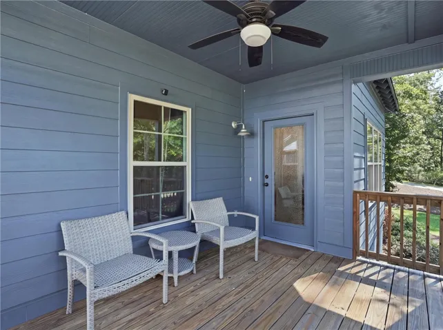 A covered wooden deck features clean siding and views of the surrounding trees.