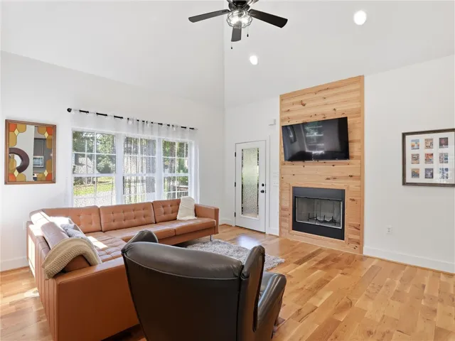 Rich hardwood flooring complements a towering vaulted ceiling and a wood-accented fireplace surround.