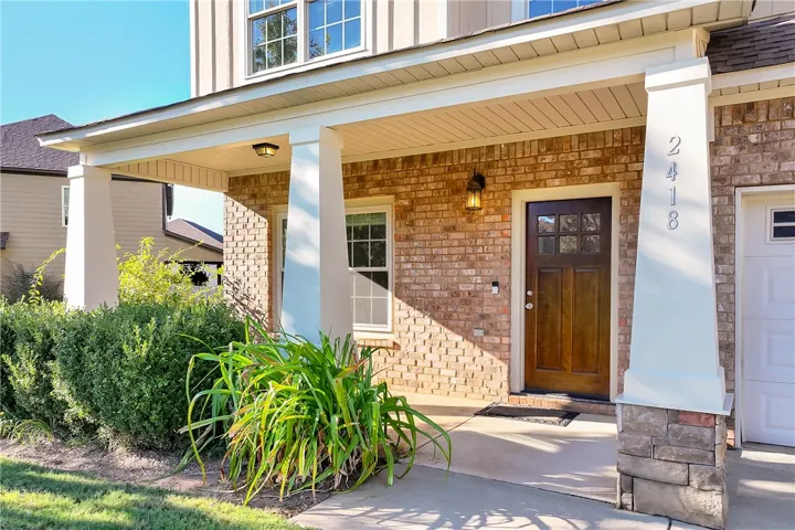 An inviting covered front porch welcomes visitors with Craftsman-style columns and brick siding.