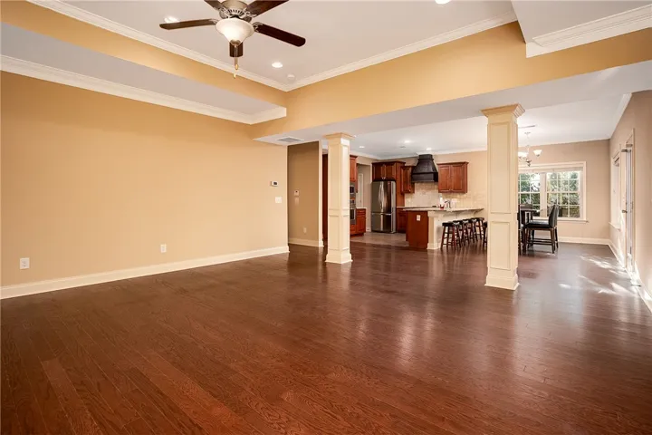 Rich hardwood floors sweep across an open-concept living area supported by classic architectural columns.