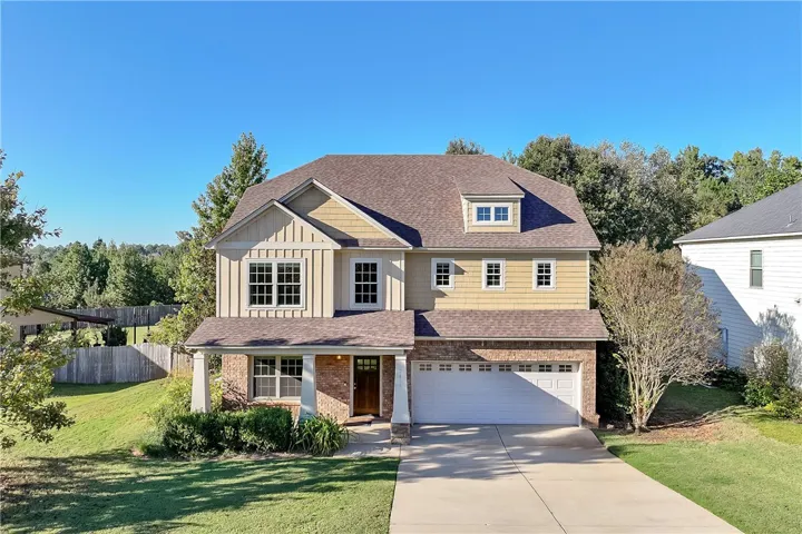 An inviting front elevation showcases classic brick and cement board siding details under a clear blue sky.