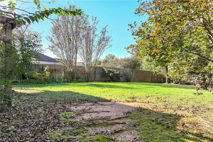Mature trees frame a spacious, fully fenced lawn perfect for outdoor activities.