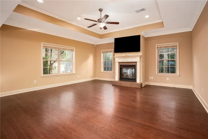 Rich hardwood floors complement the elegant tray ceiling and central fireplace in this gathering space.