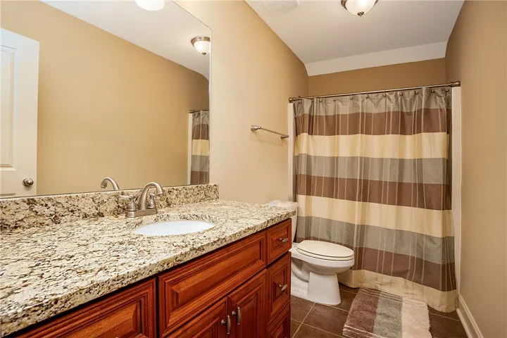 Polished granite countertops and classic wood cabinetry enrich this well-appointed bathroom space.