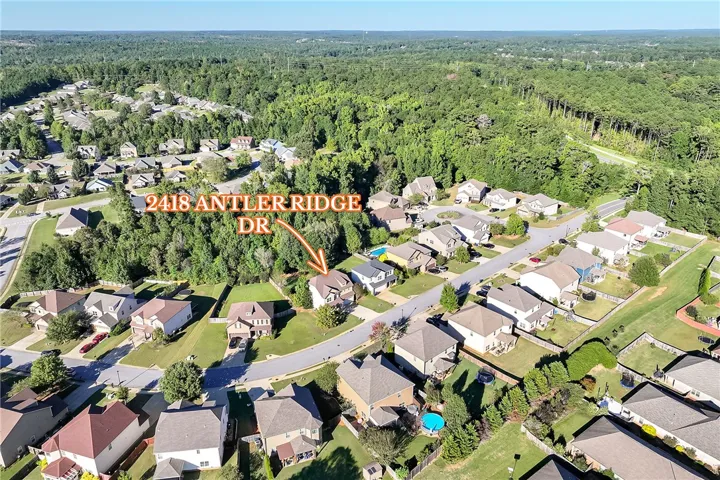 An aerial perspective showcases a quiet residential neighborhood nestled against a dense forest canopy.