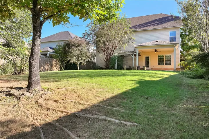 Mature trees shade a sloping lawn that leads to a covered back porch.