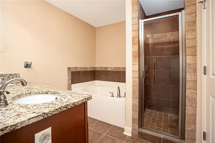 Tiled flooring and a separate walk-in shower flank a deep soaking tub.