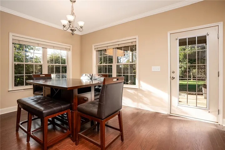 Gleaming hardwood floors and classic crown molding frame a sunlit dining area with garden views.