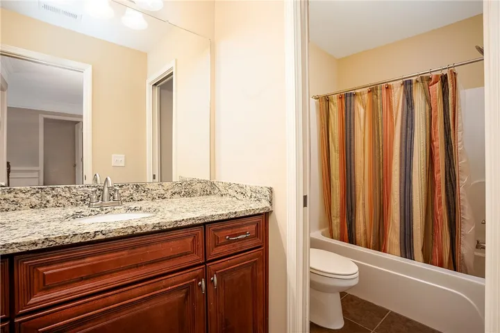 Polished stone countertops and wood cabinetry elevate this classic bathroom layout.