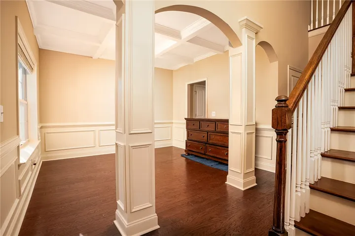 Elegant columns and detailed wainscoting define this welcoming entryway featuring rich hardwood flooring.