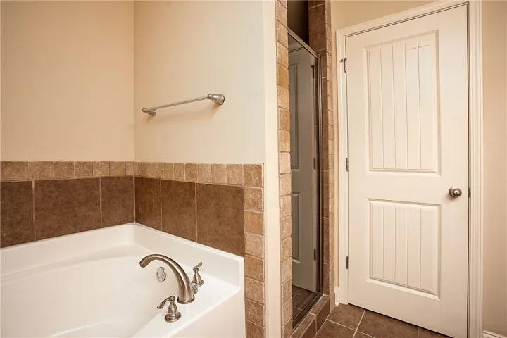 Elegantly tiled walls frame a deep soaking tub and a walk-in shower.